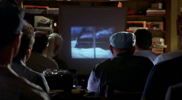 photo of the backs of people viewing a movie of a train on a track