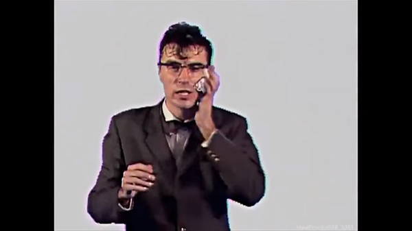 Screenshot, "Once in a Lifetime." Byrne wipes his sweat while trying to remain in control.